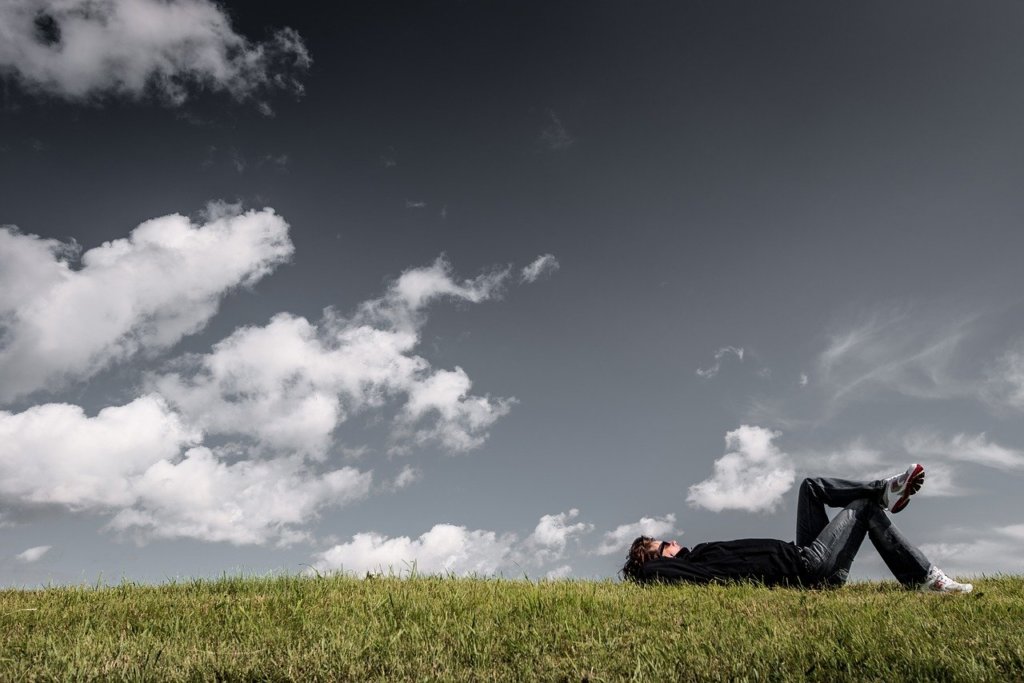 芝生に横たわって空を見上げる男性